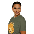 T-shirt featuring “Peace, Be Still”, sunrise detail and coffee detail and vintage lettering; purposeful character.